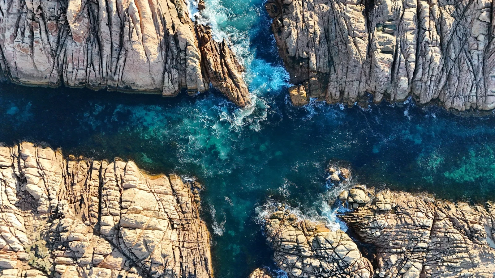 An aerial view of a rocky coastline with blue water